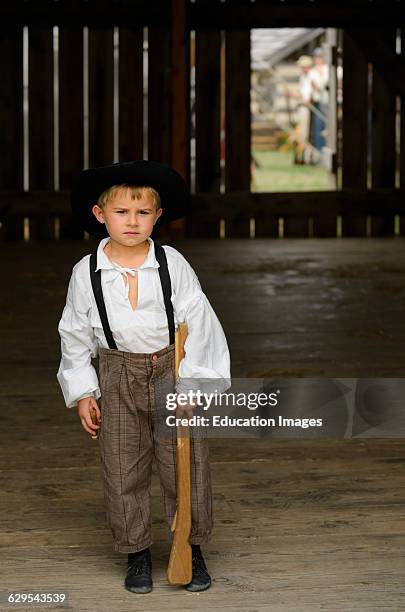 Young boy in period costume with toy rifle in a barn at a US civil war re-enactment.