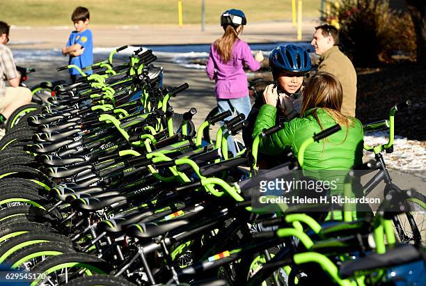 Christine Ford, from Bicycle Village, puts a helmet onto Gabe Navarro as he picks out his new Rock It bike on the playground at Summit Summit...