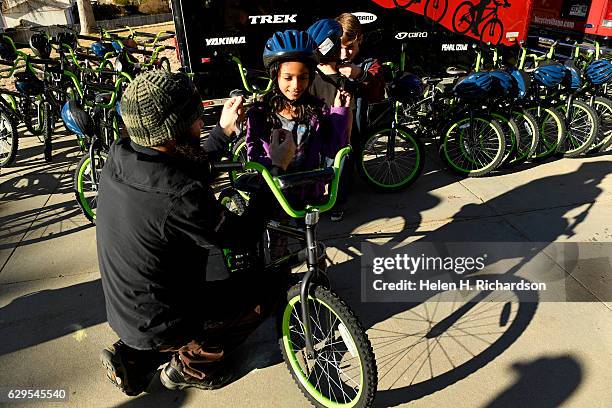 Analicia Gazotti right, gets help with her new Rock It bike from Kevin Wilkinson, left, of Bicycle Village, on the playground at Summit Summit...