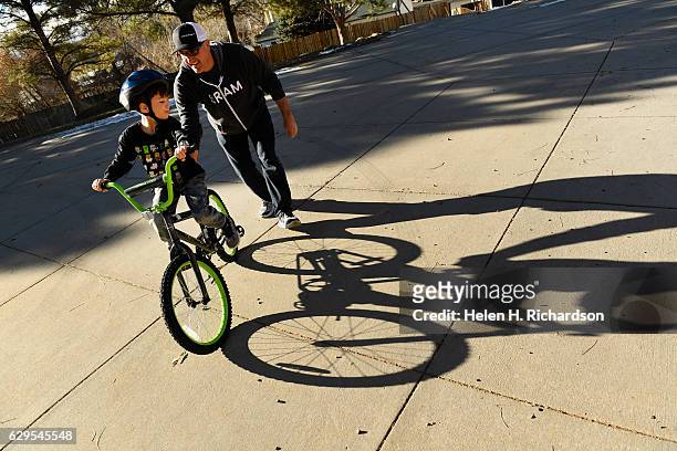 David Mancuso left, gets help learning to ride his new Rock It bike from volunteer Brad Isciyan, right, on the playground at Summit Summit Elementary...