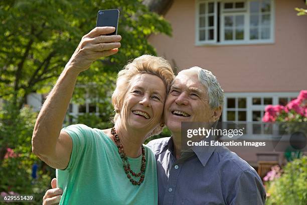 Elderly couple taking a selfie photo with a mobile phone.