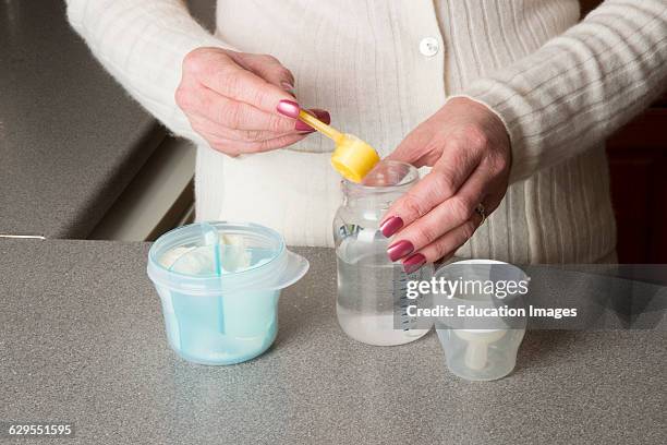 Mature mother making a babys powdered milk drink.