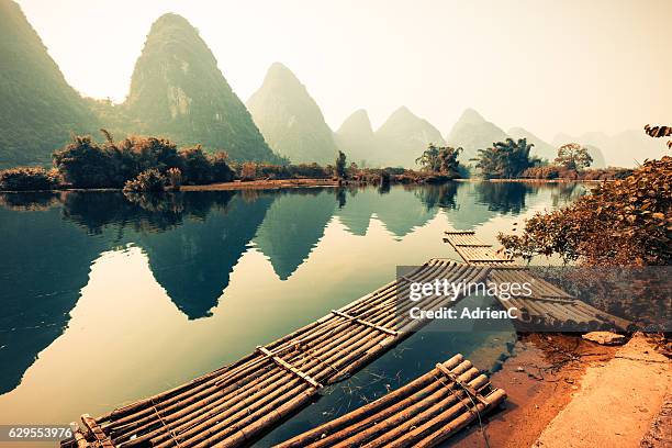 typical view from yangshuo with karst and bamboo boat on a river in a day - li river stock pictures, royalty-free photos & images