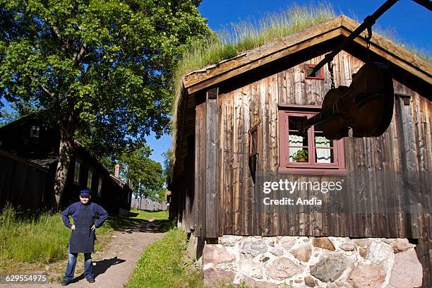 Traditional wooden house with a green roof at Turku in southern Finland and sign in the shape of a violin. Scandinavia, tourist destination.