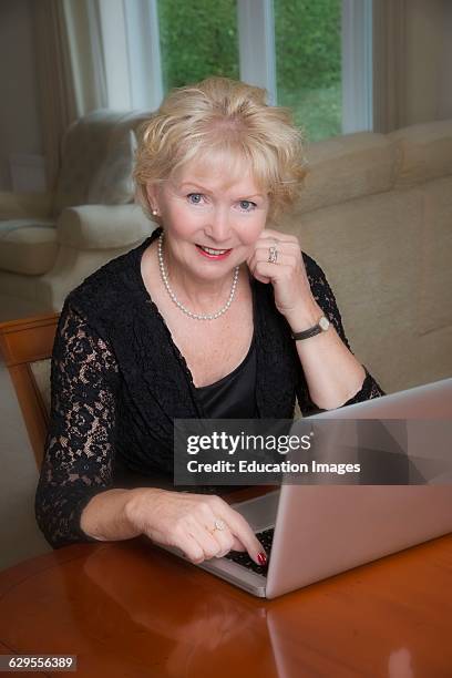 Elderly woman in a black dress using a laptop computer.