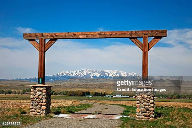 View through Montana ranch entrance to rangeland with a view of central Montanas snow covered Crazy Mountains in the background, The Crazy Mountains...