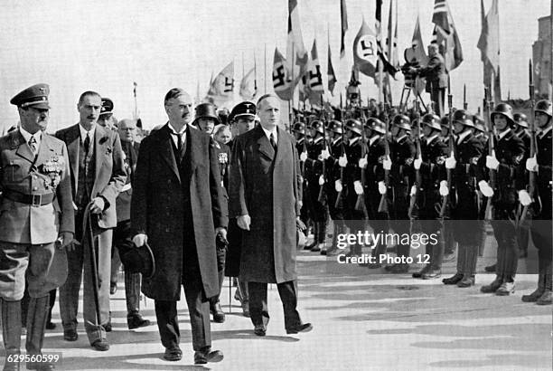 British Prime Minister Neville Chamberlain passes a Nazi honour guard on his arrival at Oberwiesenfeld airport before a meeting with Adolf Hitler...