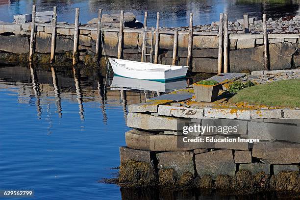 White dingy and granite wharfs in harbor Vinalhaven Island Maine New England USA.