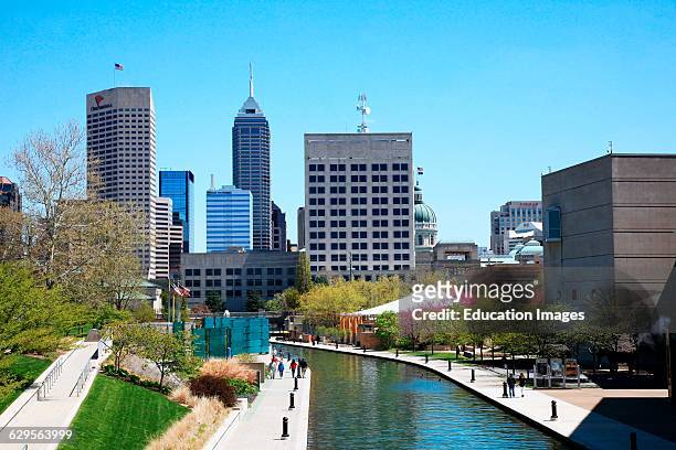 People enjoy a sunny spring day and the city skyline along the Canal Walk in downtown Indianapolis Indiana, The Canal Walk is a large linear park and...