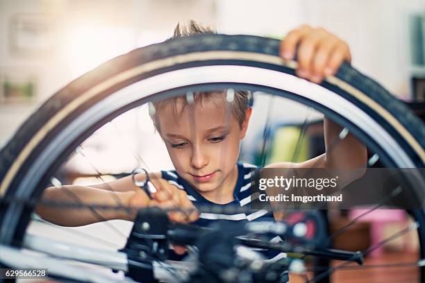 little boy repairing a bicycle at home - bicycle repair stock pictures, royalty-free photos & images