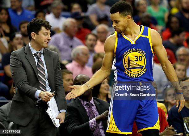 Associate Head Coach Darren Erman gives Stephen Curry of the Golden State Warriors five after Curry scored a three pointer during the second half at...