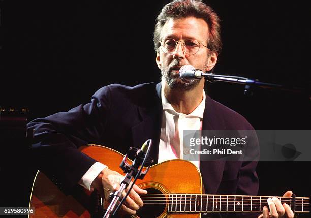 Eric Clapton performs on stage playing acoustic guitar at the Royal Albert Hall, London, 1998.