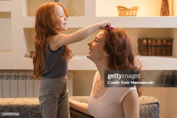 adorable little girl combing her mother's  hair. - combing bildbanksfoton och bilder