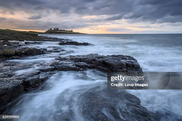 Dunstanburgh Castle viewed from the south with a stormy sea in the foreground, Dunstanburgh, England.