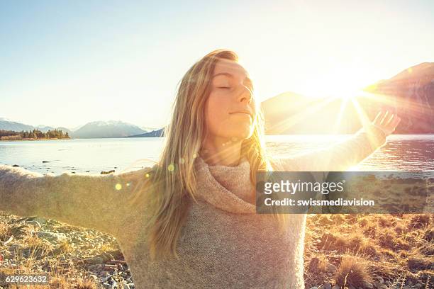 young woman relaxing by the lake, mountain fresh air - breathing exercise stockfoto's en -beelden