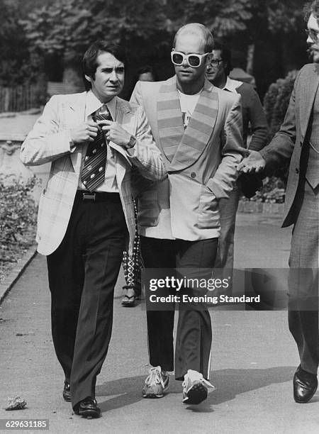 English singer-songwriter Elton John with his manager John Reid, on their way to a luncheon in honour of Buddy Holly at the Orangery in Holland Park,...