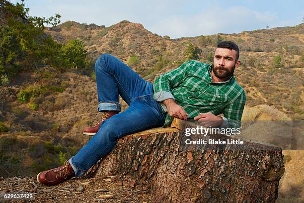 bearded man lying on stump - lumberjack stock pictures, royalty-free photos & images