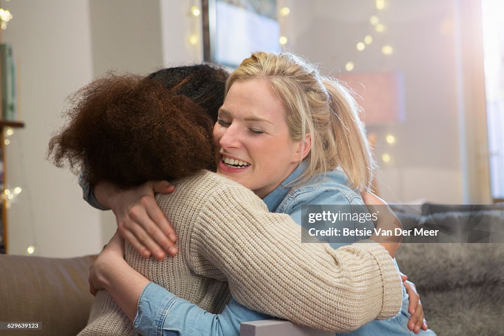 Women embrace eachother in livingroom.