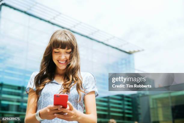 woman using smart phone with offices - movilidad fotografías e imágenes de stock