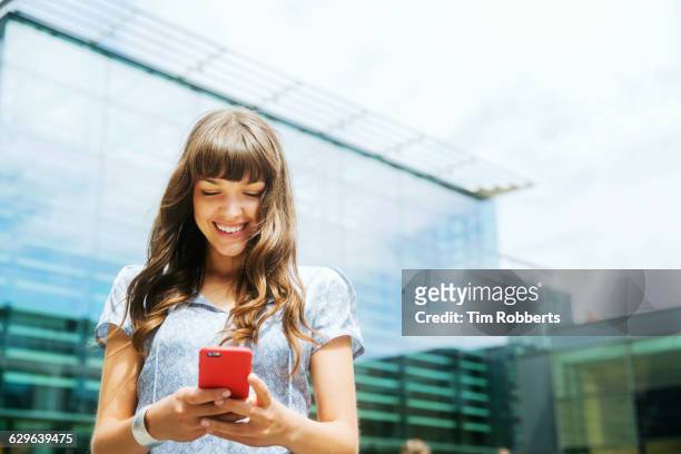 woman using smart phone with offices - woman with smartphone stockfoto's en -beelden