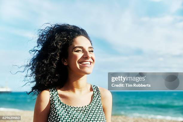 smiling woman on beach. - capelli ricci foto e immagini stock