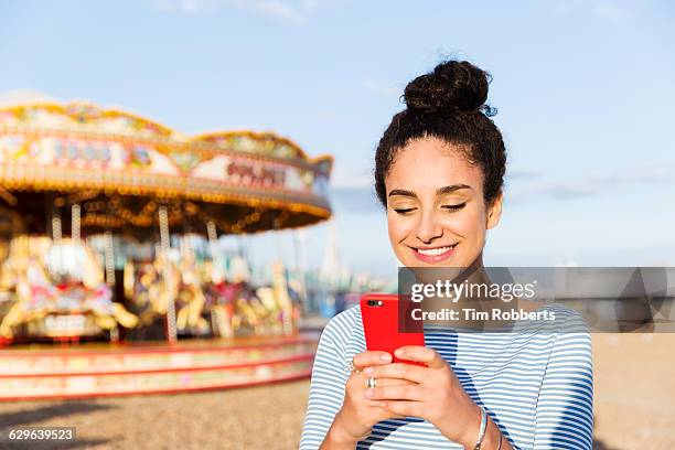 woman text messaging at beach fairground - young woman beach smiling stock pictures, royalty-free photos & images