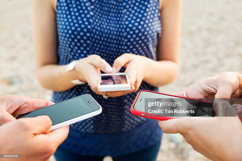 Close up of 3 people using smart phones