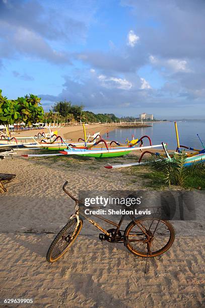 rusty old bike on balinese beach at sunrise - by sheldon levis stock pictures, royalty-free photos & images