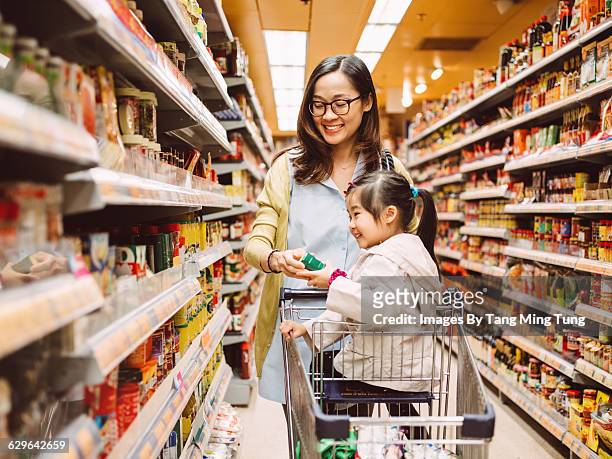 mom & daughter shopping at supermarket - shopping cart groceries stock-fotos und bilder