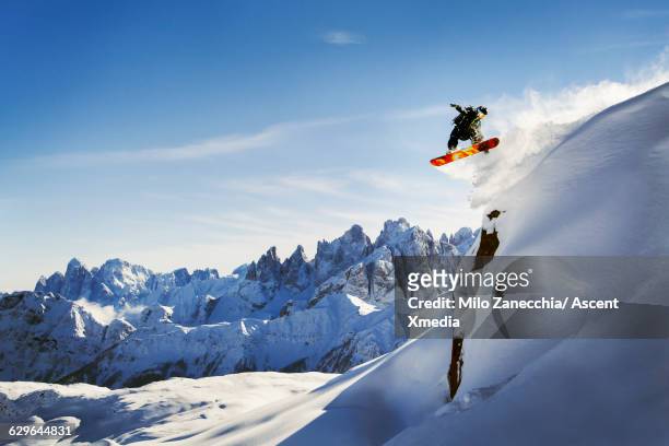 snowboader in mid air flight over snow cliff, - adrenalina fotografías e imágenes de stock