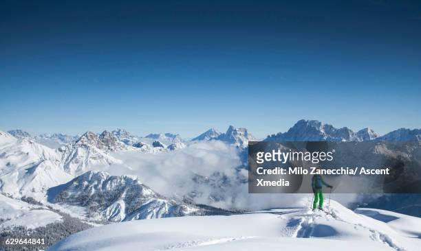ski mountaineer pauses on mountain ridge crest - mountain snow skiing foto e immagini stock