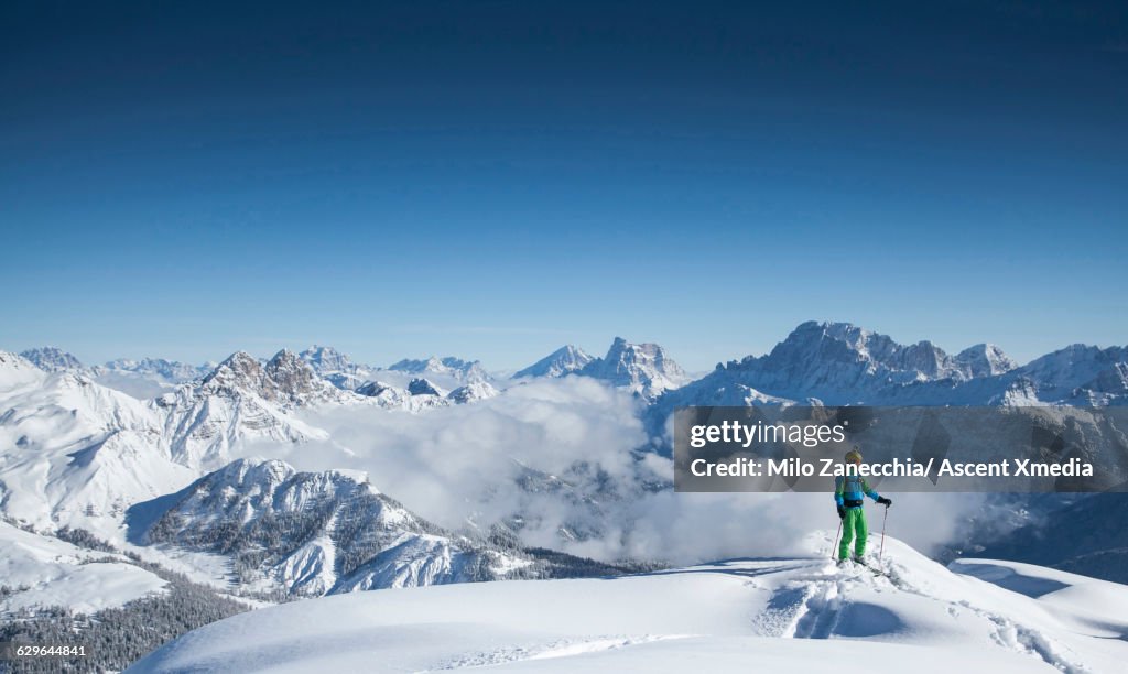 Ski mountaineer pauses on mountain ridge crest