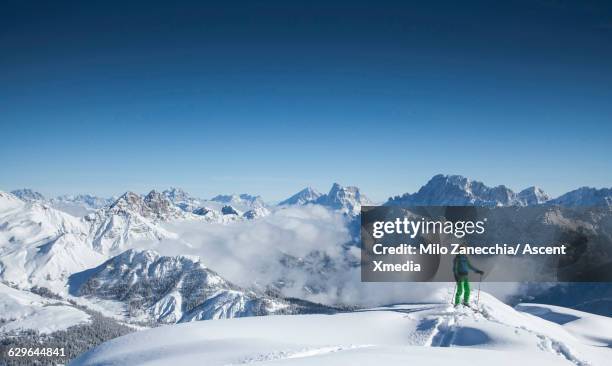 ski mountaineer pauses on mountain ridge crest - dolomiti stock pictures, royalty-free photos & images