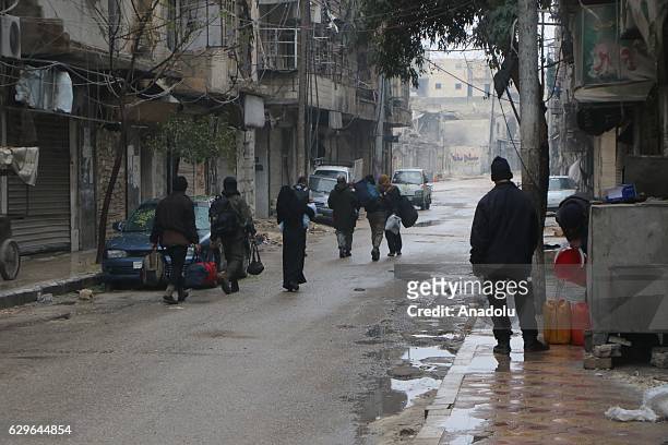 Civilians stuck in al-Mashhad neighborhood walk through a street to reach the area where the evacuation of the civilians will take place in Aleppo,...