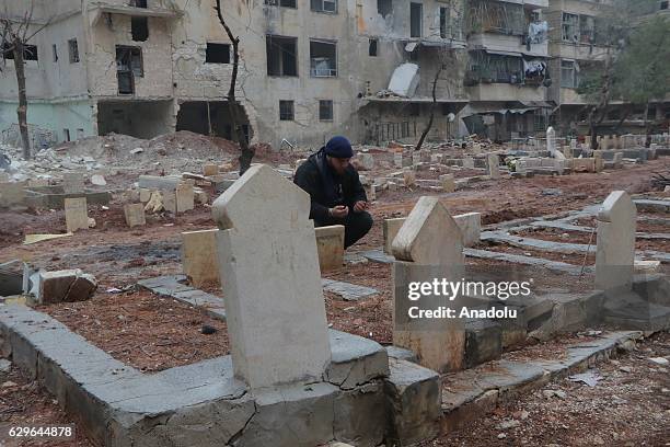 Man prays over the graves of family members in al-Mashhad neighborhood in Aleppo, Syria on December 14, 2016.