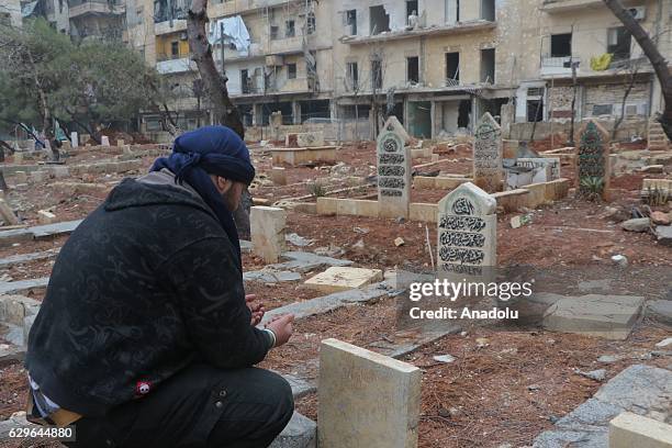 Man prays over the graves of family members in al-Mashhad neighborhood in Aleppo, Syria on December 14, 2016.