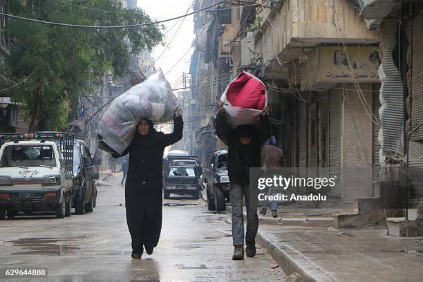 Civilians stuck in al-Mashhad neighborhood walk through a street to reach the area where the evacuation of the civilians will take place in Aleppo,...