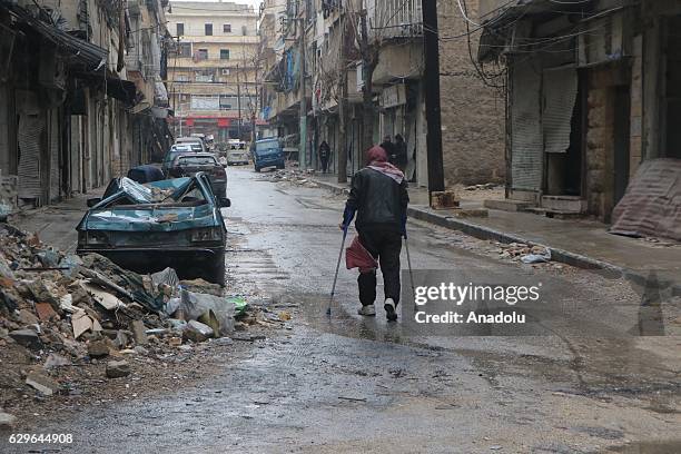 Man, one of civilians stuck in al-Mashhad neighborhood, walks with crutches through a street to reach the area where the evacuation of the civilians...