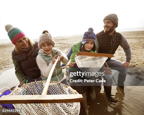 Family With Fishing Nets On Beach In Winter High-Res Stock Photo