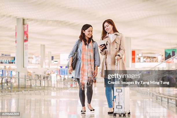 two ladies looking at passport at airport - rolling luggage stock pictures, royalty-free photos & images