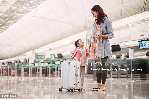 mom & daughter waiting at check in counters - airport family stock-fotos und bilder