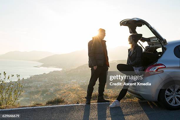 two hikers pause against car above the sea - coastal feature stock pictures, royalty-free photos & images