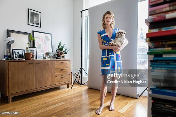 young woman holding her pet dog in apartment - donne bionde scalze foto e immagini stock