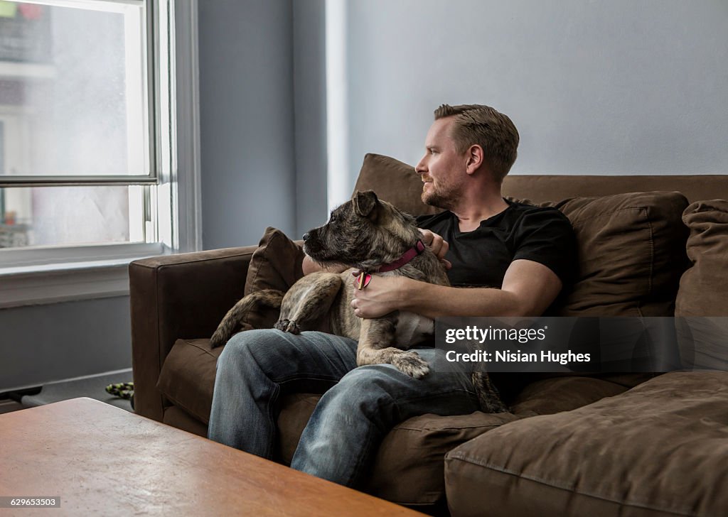 Portrait of man sitting on couch with pet dog
