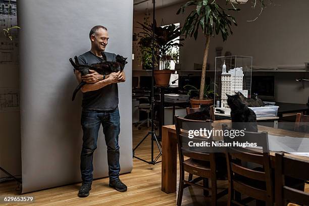 man holding pet cat on gray background - holding cat stock-fotos und bilder