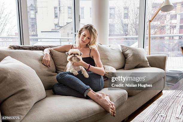 woman sitting on couch with her pet dog - grey jeans stock pictures, royalty-free photos & images