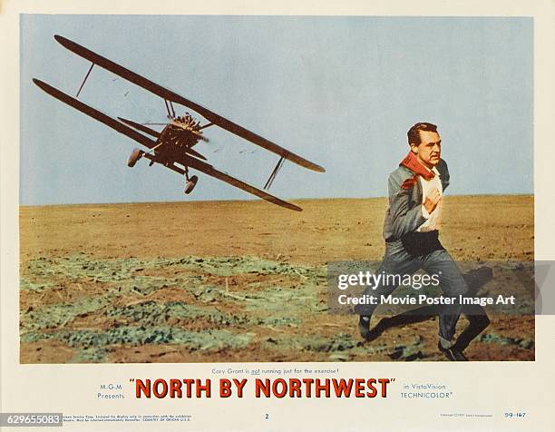 Actor Cary Grant flees from a crop duster plane on a lobby card for Alfred Hitchcock's 1959 thriller 'North by Northwest', an MGM film.