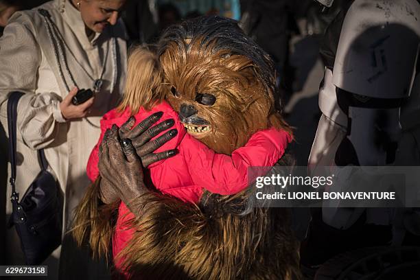 Person dressed as Chewbacca of Star Wars hugs a child on December 14, 2016 at the Grand Rex cinema in Paris on the first day of the European release...