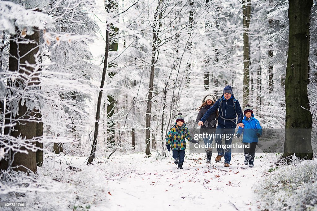 Father with kids running in beautiful winter forest