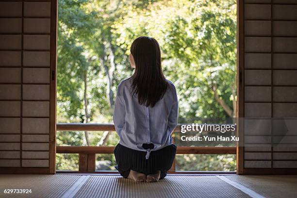 girl sitting in traditional japanese house looking out - shoji fotografías e imágenes de stock
